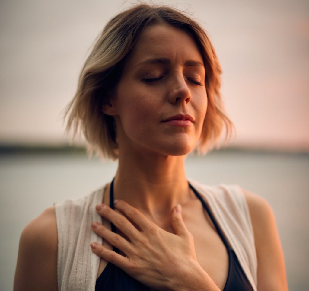 Photo d'une femme avec la main sur le coeur en plan serré sur le visage.